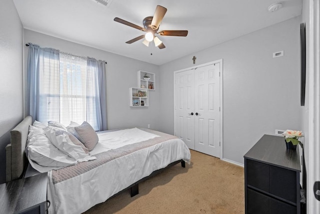 bedroom with a closet, light carpet, and a ceiling fan