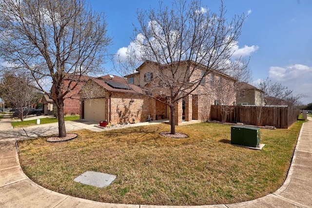 view of front of house featuring a front lawn, driveway, roof mounted solar panels, fence, and brick siding