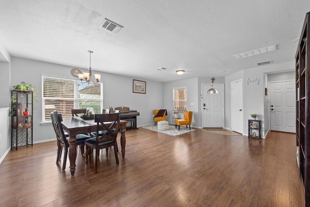 dining area with visible vents, a textured ceiling, and dark wood-style flooring