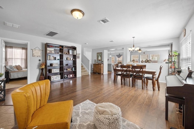 living room featuring a notable chandelier, visible vents, and wood finished floors