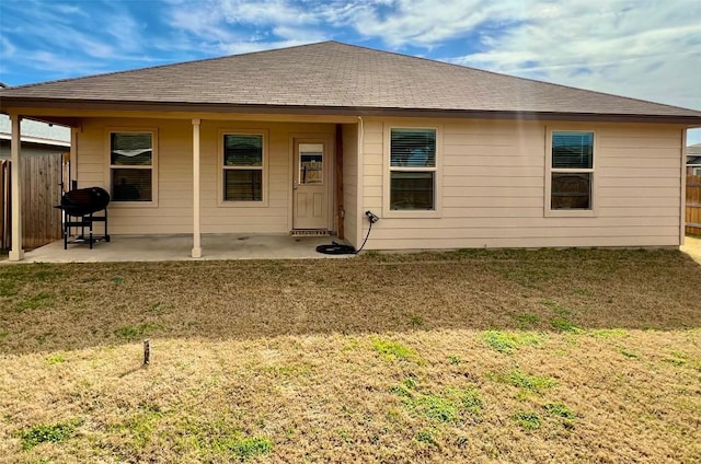 rear view of house featuring a patio area, fence, a lawn, and roof with shingles