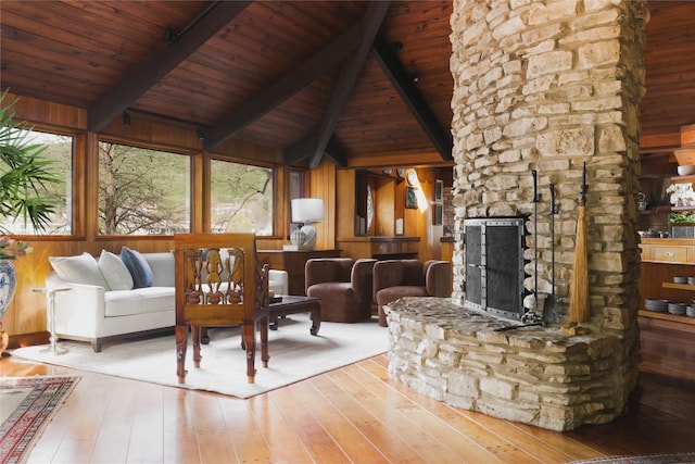 unfurnished living room with wooden walls, a fireplace, lofted ceiling with beams, and wood-type flooring