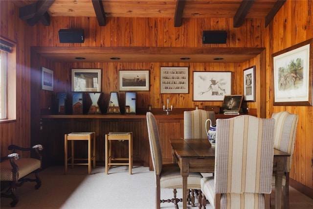 dining room featuring beam ceiling, wooden walls, wood ceiling, and wet bar