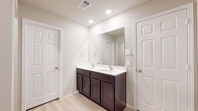 bathroom featuring double vanity, wood finished floors, visible vents, and a sink