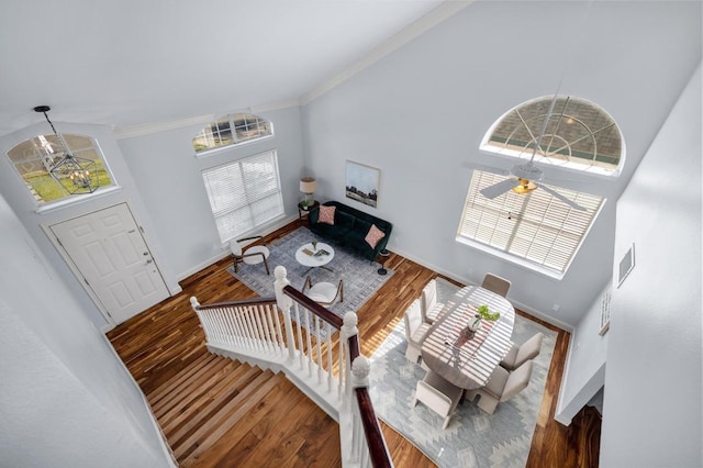 interior space featuring wood finished floors, baseboards, visible vents, a high ceiling, and ornamental molding