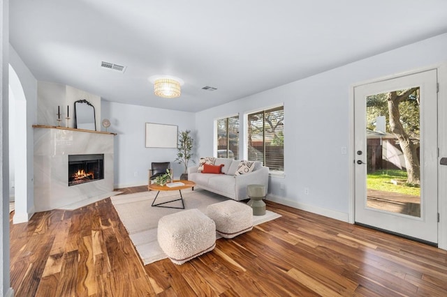 living area featuring visible vents, baseboards, wood finished floors, and a tiled fireplace