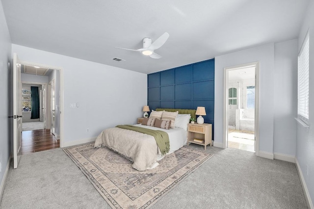 carpeted bedroom with a ceiling fan, baseboards, visible vents, attic access, and ensuite bath