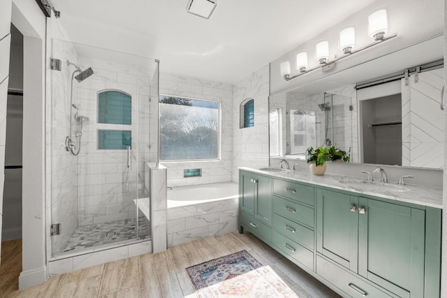 bathroom featuring a garden tub, double vanity, a stall shower, and a sink