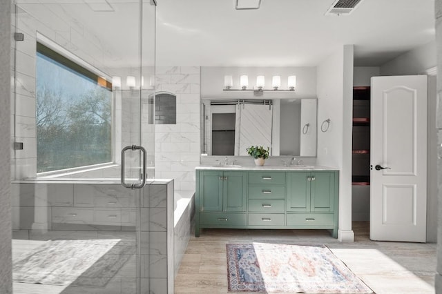 full bath with visible vents, a washtub, double vanity, a stall shower, and a sink