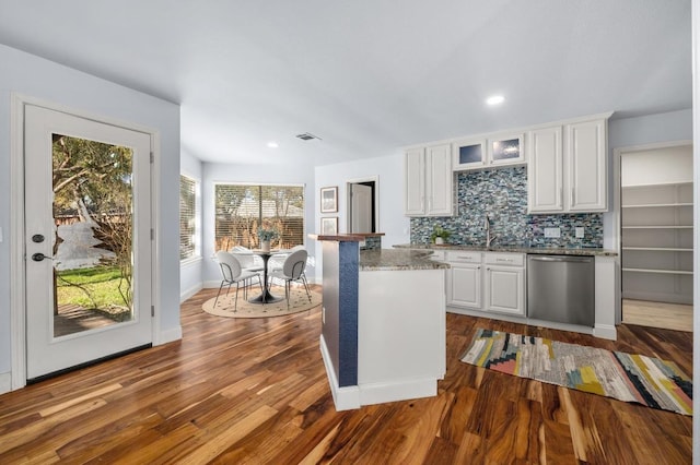 kitchen featuring tasteful backsplash, stainless steel dishwasher, dark wood-style floors, and white cabinets