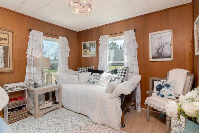 bedroom featuring multiple windows, wood walls, and wood finished floors