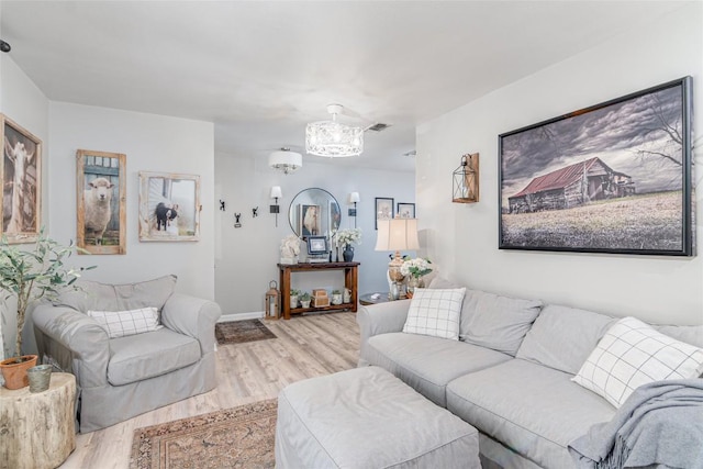 living area with a chandelier, light wood-type flooring, and baseboards