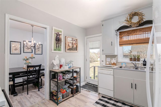 kitchen featuring dishwasher, a chandelier, light wood-style flooring, a sink, and light countertops