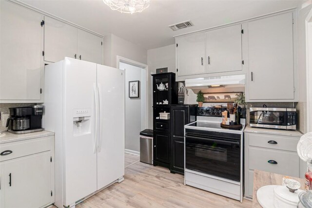 kitchen with stainless steel microwave, electric stove, white fridge with ice dispenser, under cabinet range hood, and light countertops
