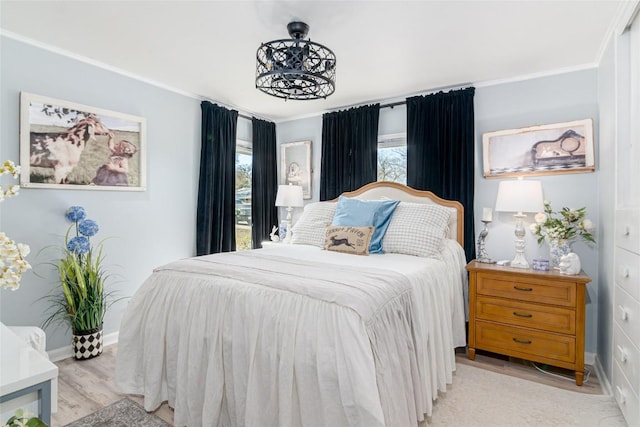 bedroom featuring light wood-type flooring, crown molding, and baseboards