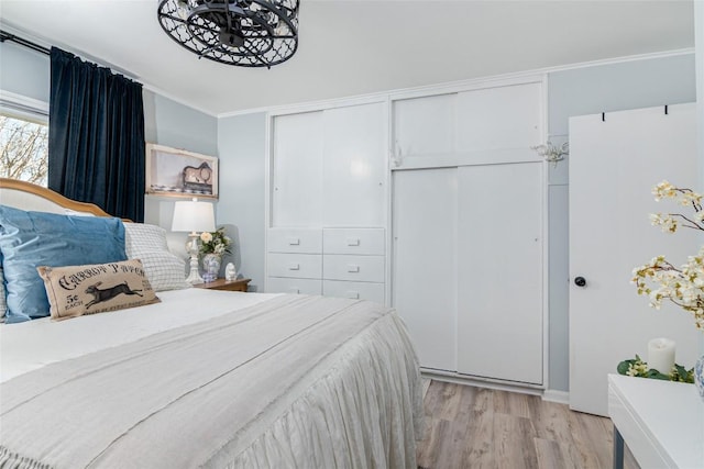 bedroom featuring a closet, light wood finished floors, and crown molding