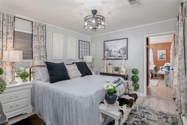 bedroom with wood finished floors, crown molding, a chandelier, and baseboards