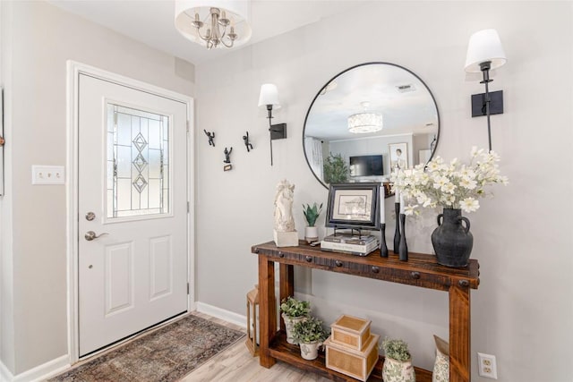 foyer entrance with baseboards, wood finished floors, and a chandelier