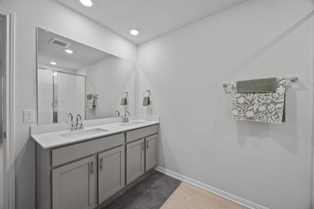 bathroom with double vanity, wood finished floors, visible vents, and a sink