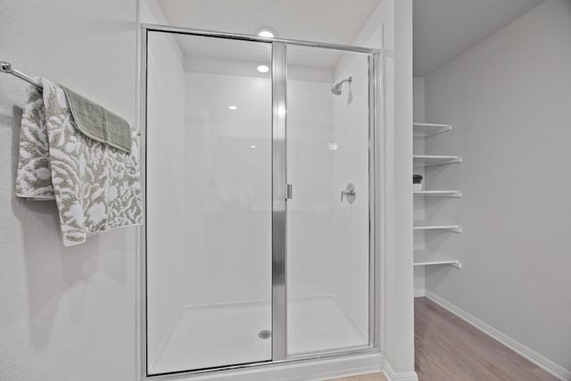 bathroom featuring a shower stall, wood finished floors, and baseboards