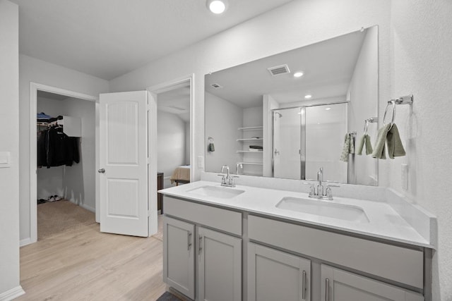 bathroom featuring a stall shower, wood finished floors, visible vents, and a sink