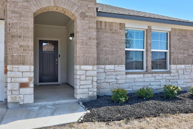 entrance to property with stone siding and roof with shingles