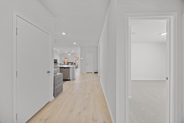 hall featuring light wood-style flooring, recessed lighting, and baseboards