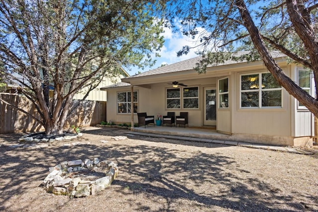 back of house featuring a shingled roof, a fire pit, ceiling fan, fence, and a patio area