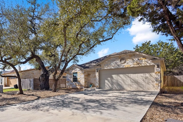 single story home with stone siding, driveway, an attached garage, and fence