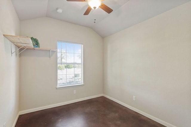 spare room featuring baseboards, concrete flooring, and vaulted ceiling