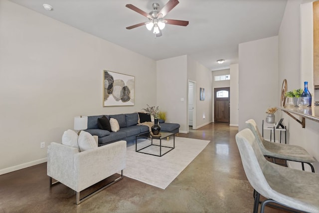 living area with ceiling fan, baseboards, and finished concrete floors