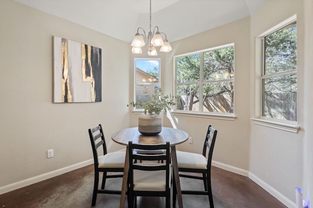 dining area featuring a notable chandelier, concrete flooring, baseboards, and vaulted ceiling