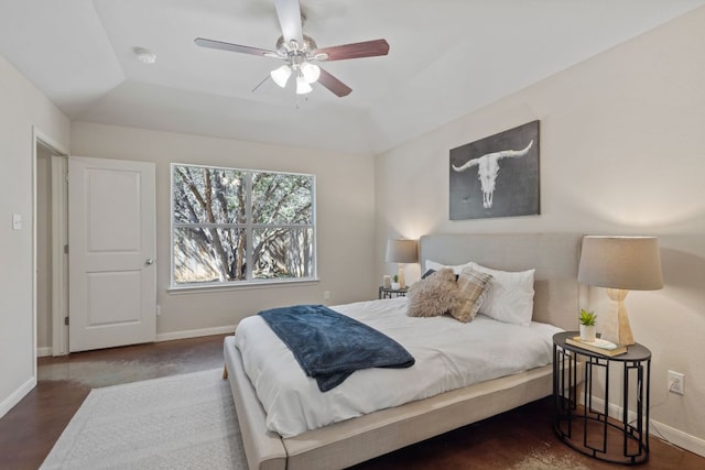 bedroom with a ceiling fan, a raised ceiling, and baseboards