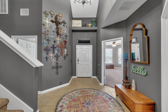 tiled foyer entrance featuring stairs, baseboards, and visible vents