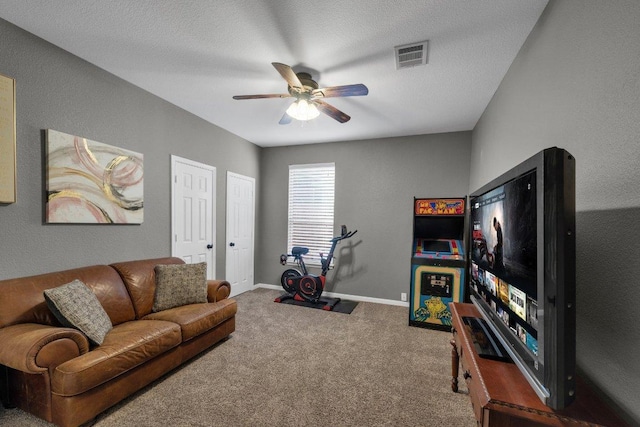 carpeted living room with a textured ceiling, baseboards, visible vents, and ceiling fan