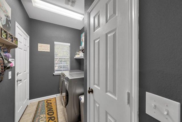 laundry room featuring laundry area, a textured wall, baseboards, and washing machine and clothes dryer