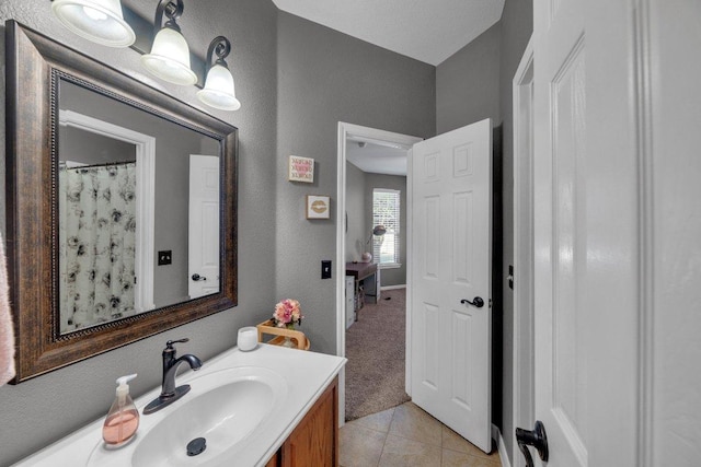 full bathroom featuring tile patterned floors, vanity, and a textured wall