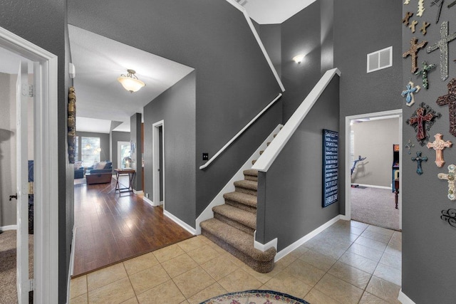 foyer featuring tile patterned floors, visible vents, baseboards, and stairs