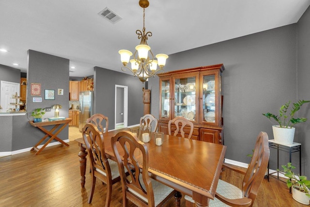 dining space with light wood finished floors, visible vents, baseboards, recessed lighting, and a notable chandelier