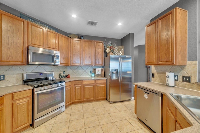 2157 Paradise Ridge Dr, Round Rock, TX 78665 - kitchen with appliances with stainless steel finishes, tasteful backsplash, light countertops, recessed lighting, and light tile patterned floors