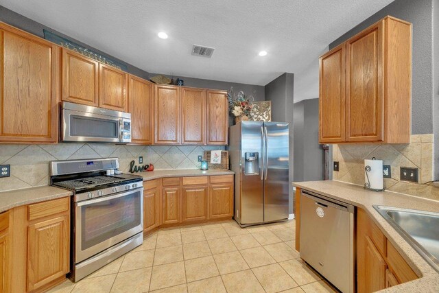 2157 Paradise Ridge Dr, Round Rock, TX 78665 - kitchen with stainless steel appliances, tasteful backsplash, light countertops, recessed lighting, and light tile patterned floors