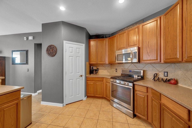 kitchen with baseboards, light tile patterned flooring, decorative backsplash, light countertops, and appliances with stainless steel finishes