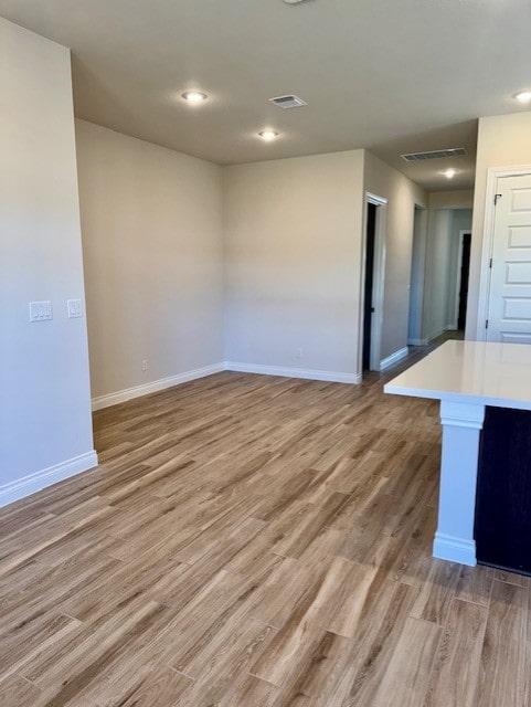 unfurnished living room with light wood-type flooring, visible vents, and baseboards