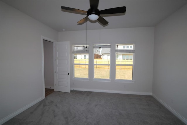 carpeted spare room featuring baseboards and a ceiling fan