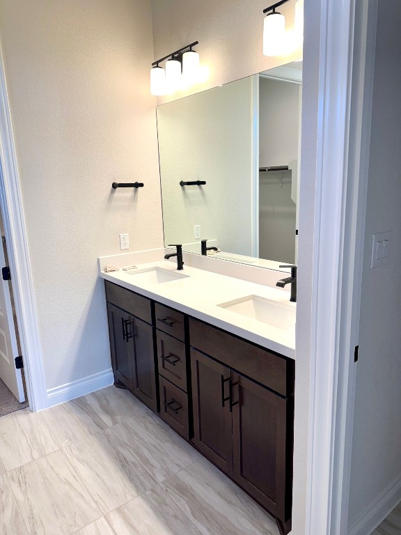 full bath with a sink, baseboards, and double vanity