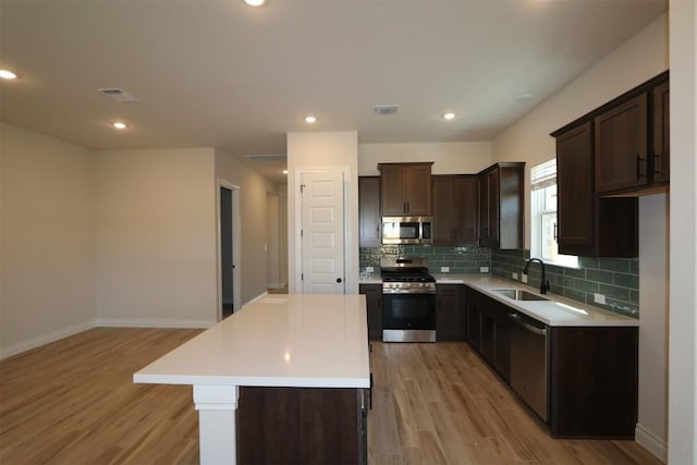 kitchen with visible vents, a sink, light wood-style floors, dark brown cabinetry, and appliances with stainless steel finishes