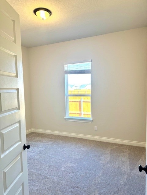 carpeted empty room featuring baseboards and a textured ceiling