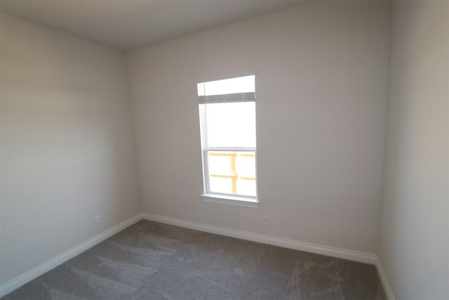 unfurnished room with baseboards and dark colored carpet