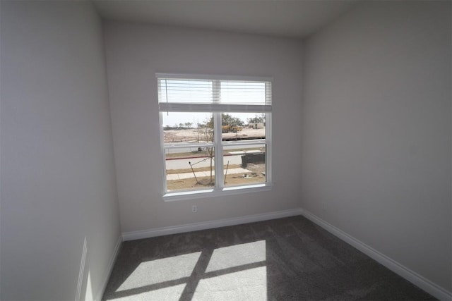 unfurnished room featuring baseboards and dark colored carpet