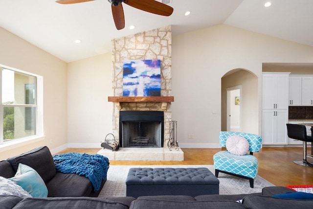 living area featuring baseboards, recessed lighting, a fireplace, arched walkways, and high vaulted ceiling